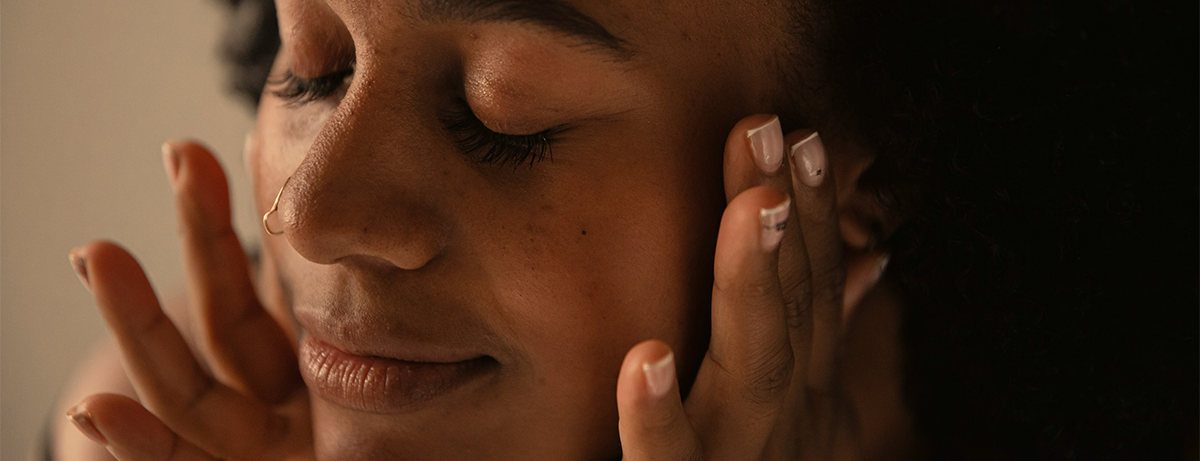 Close up of female holding hands to side of face. Happy expression
