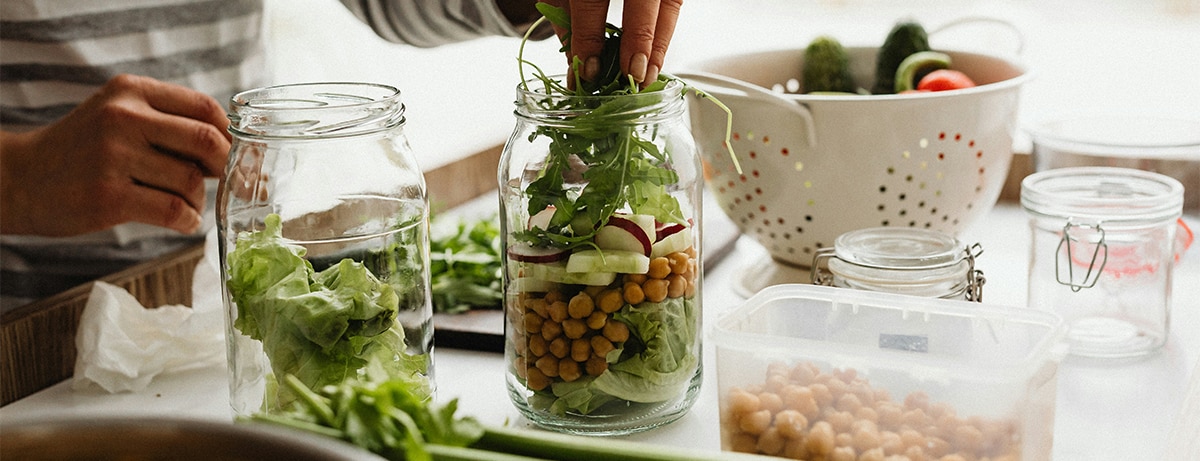 Female close up at work counter prepping healthy snacks in a jar