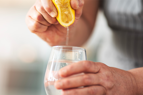 Squeezing lemon into glass of water