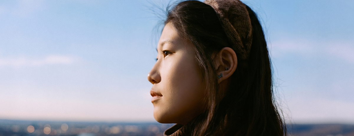 Japanese female looking away from camera with blue sky behind