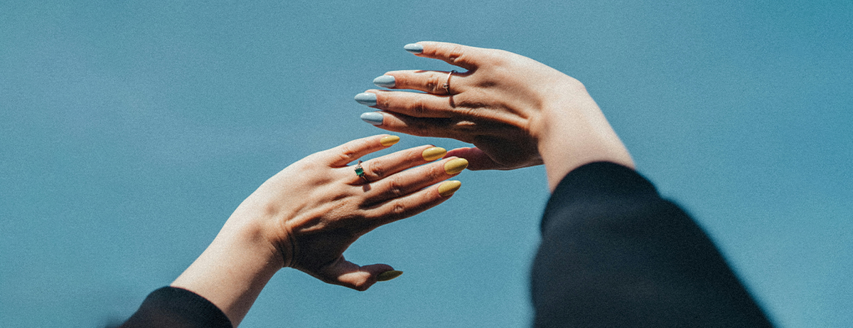 Female holding hands in the air in front of blue sky