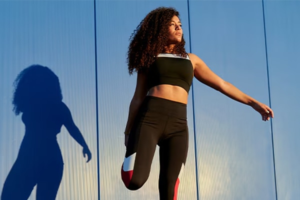 woman stretching to warm up in sports gear with sun shining on her