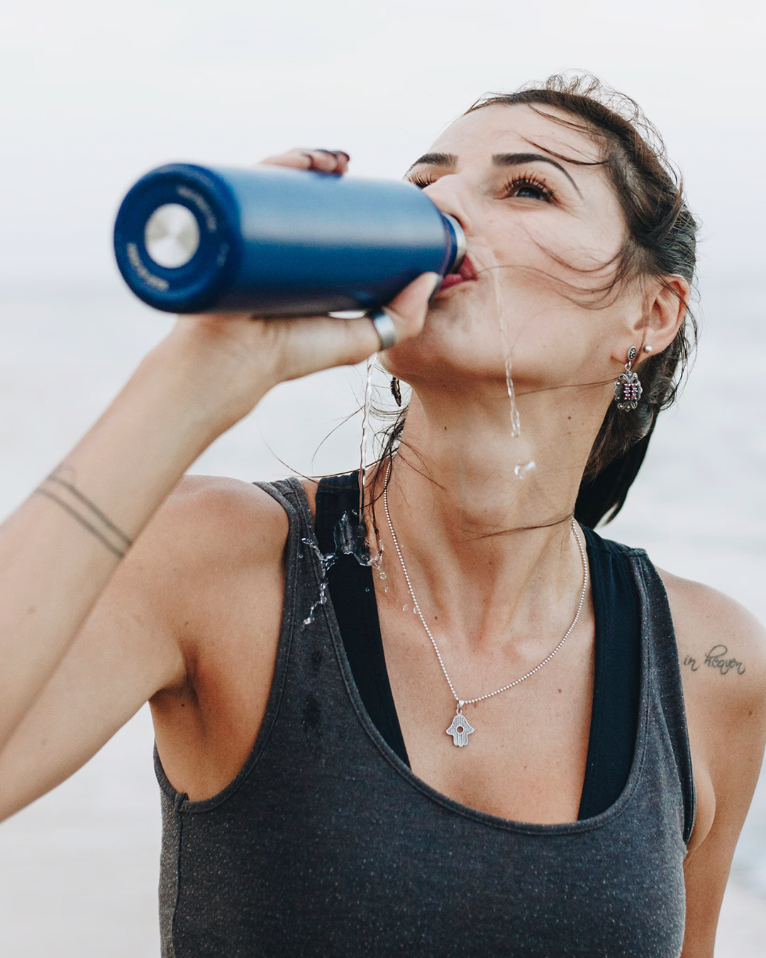 Female drinking sports drink with sea in the background