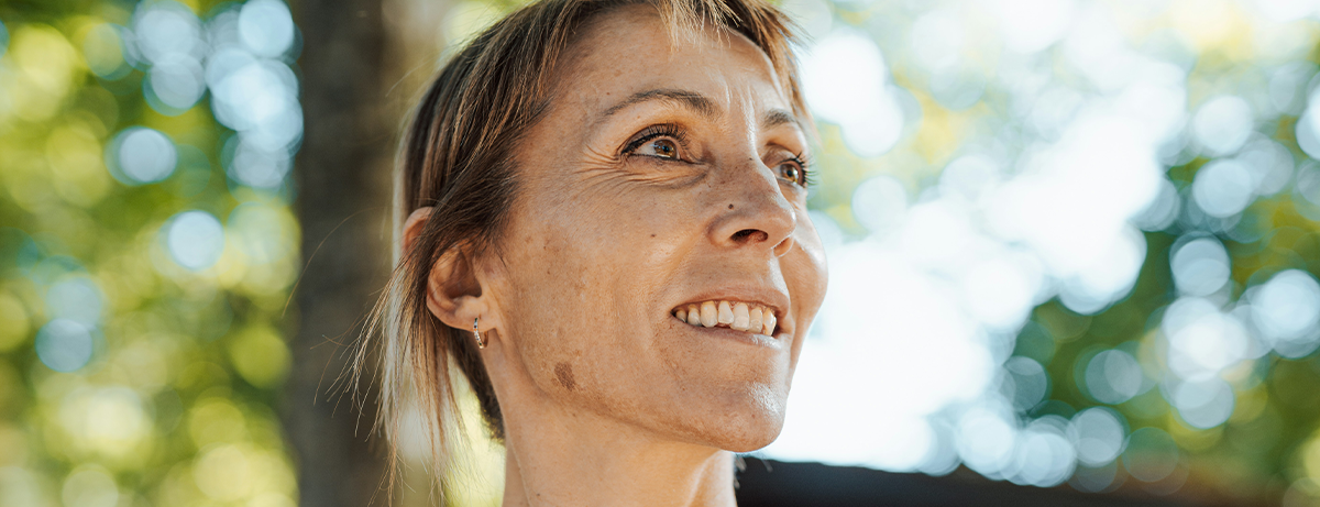 Middle aged female close up outdoors, calm expression looking away from the camera