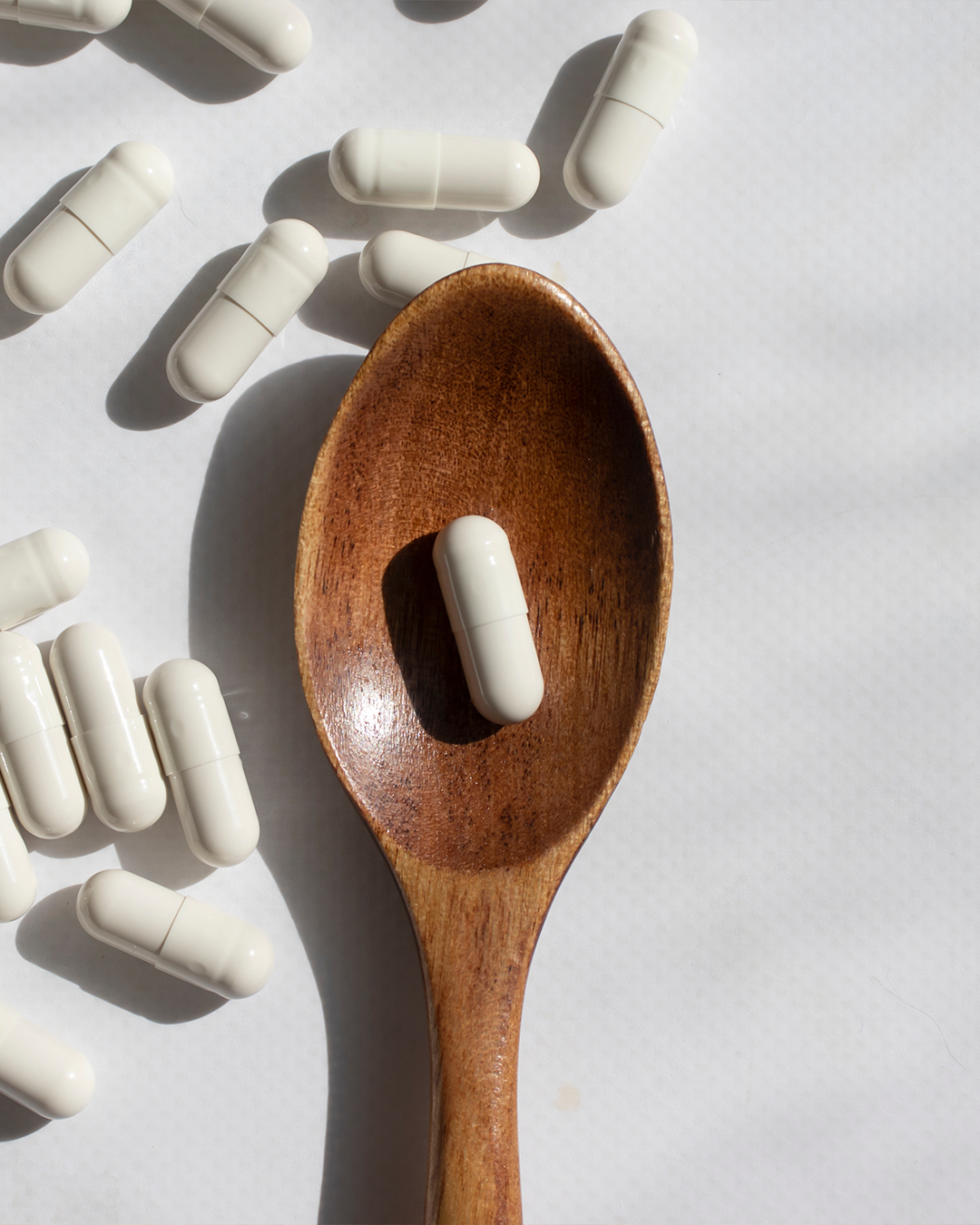 Spoon of supplements on a white background
