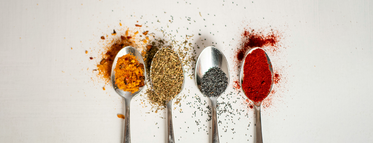 Selection of spices on silver spoons on white background