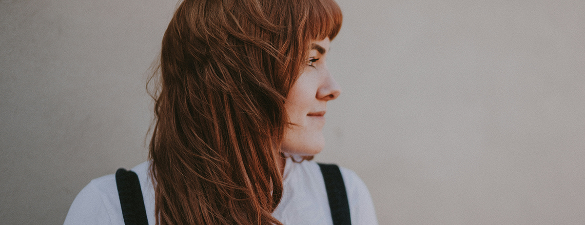 Female standing against a light wall with red hair