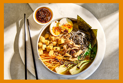 Portion of ramen in a white bowl on a marble table
