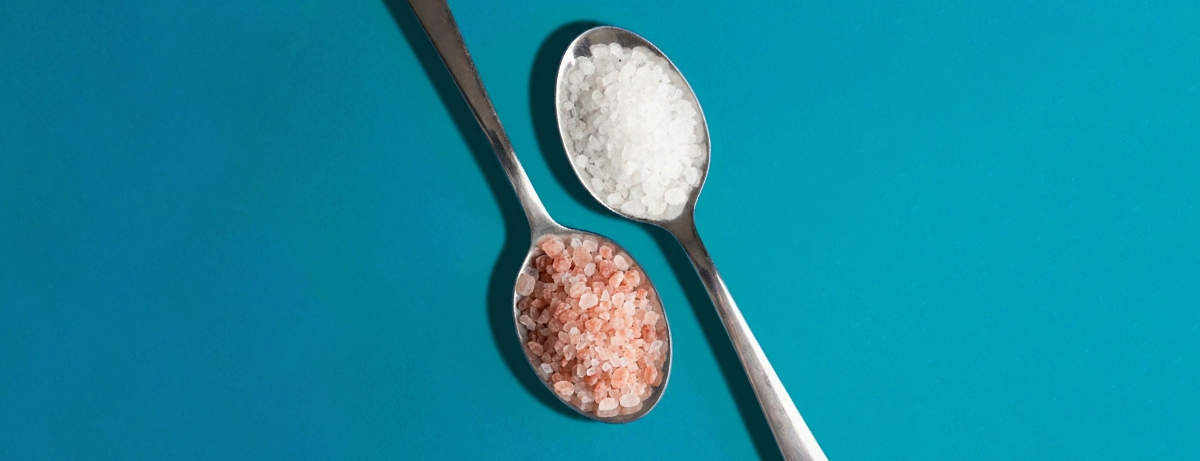 Two spoons on a blue background with salt