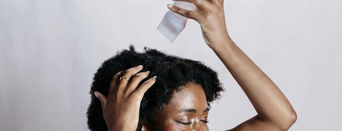 Female applying shea butter oil to her hair