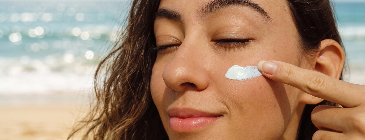 Female applying spf to face on beach