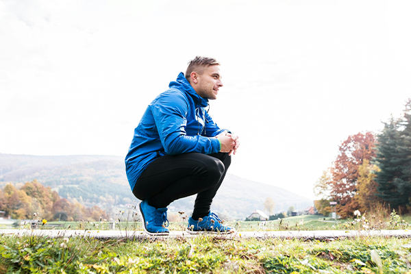 Male in gym gear kneeling down outdoors