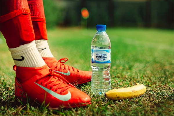 Football shoes next to a banana and bottle of water