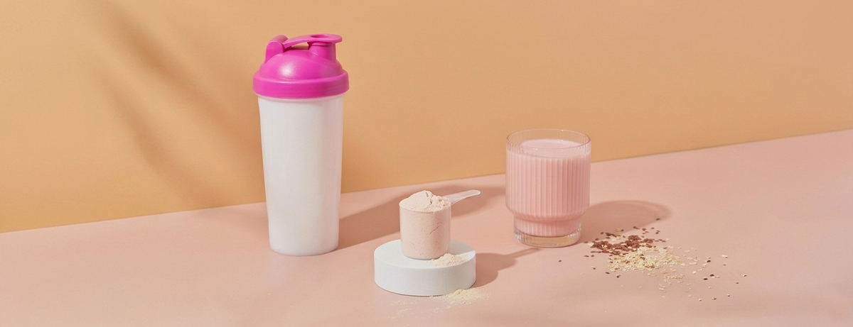 Protein shake and powder on a peach background