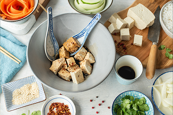 Tofu and soy sauce in bowls on white worktop
