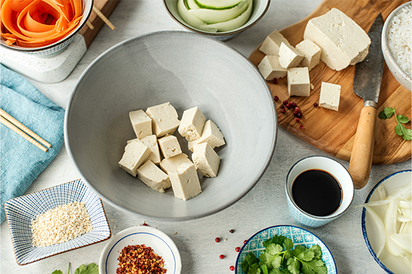 Portion of tofu in a bowl with vegetables and soy sauce