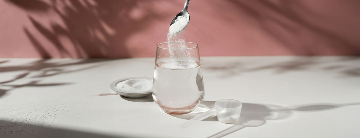 Collagen powder being poured into a glass of water
