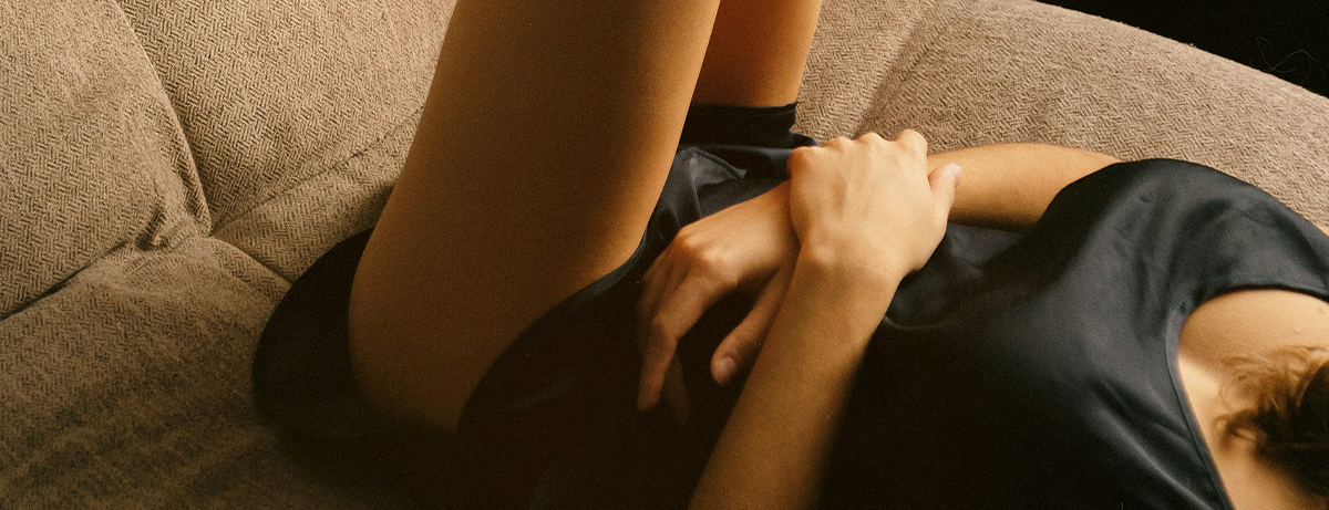 Female laying on the bed holding hands on waist