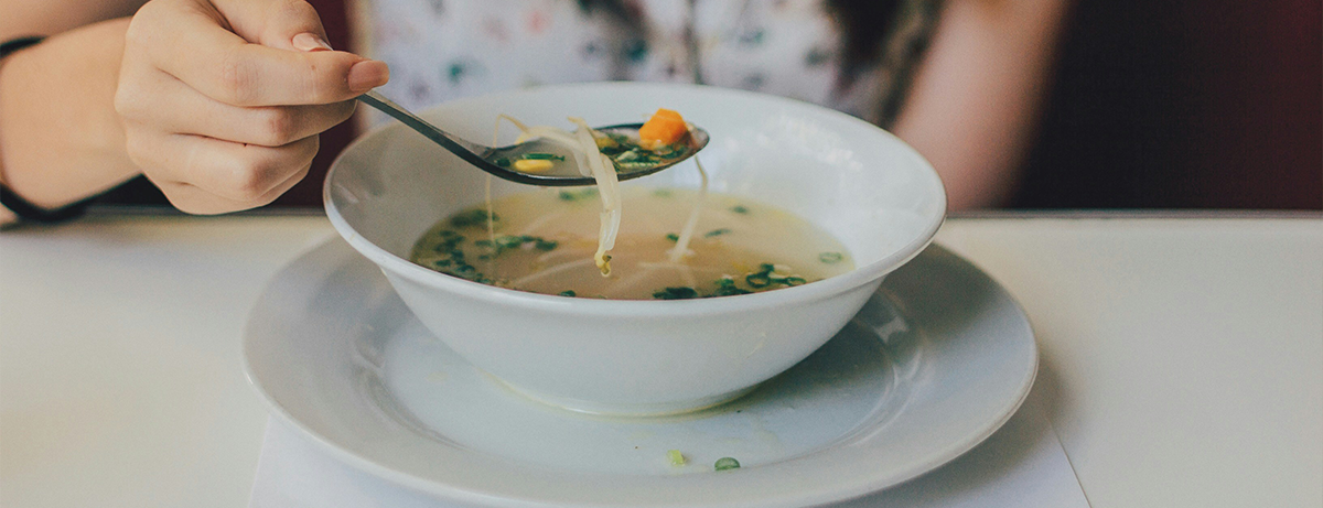 Female with a bowl of vegan broth and a spoon