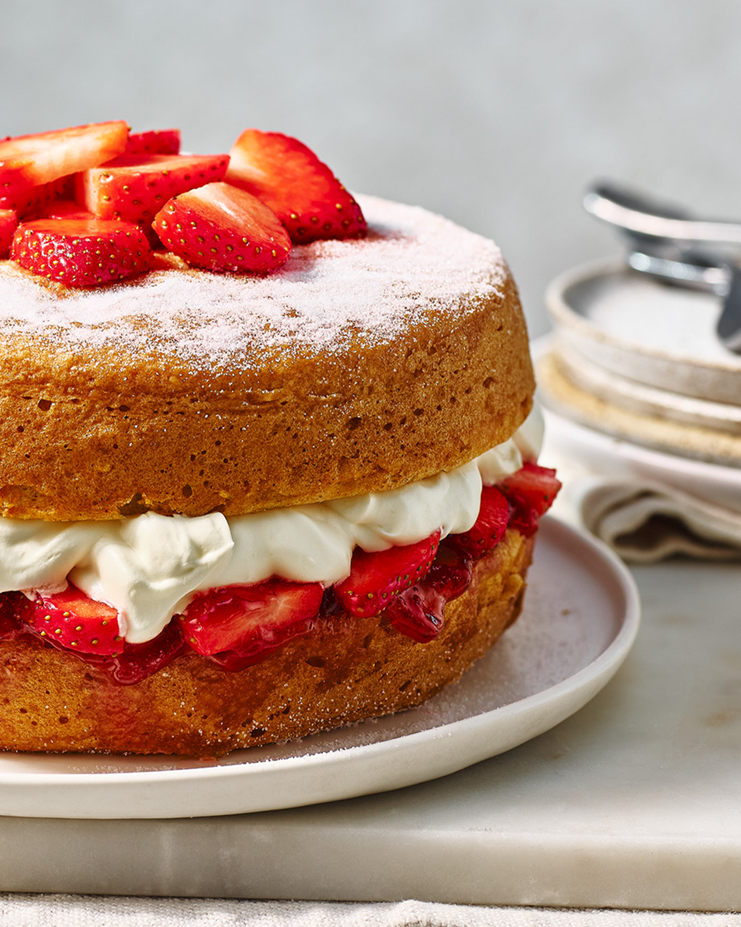 Victoria sponge cake on white plate topped with strawberries