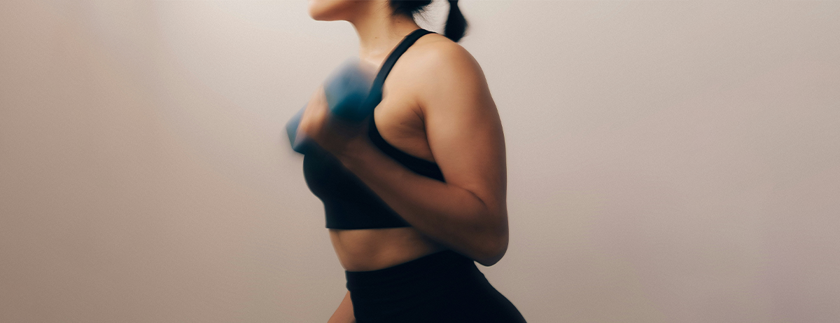 Female on beige background with dumbell weights