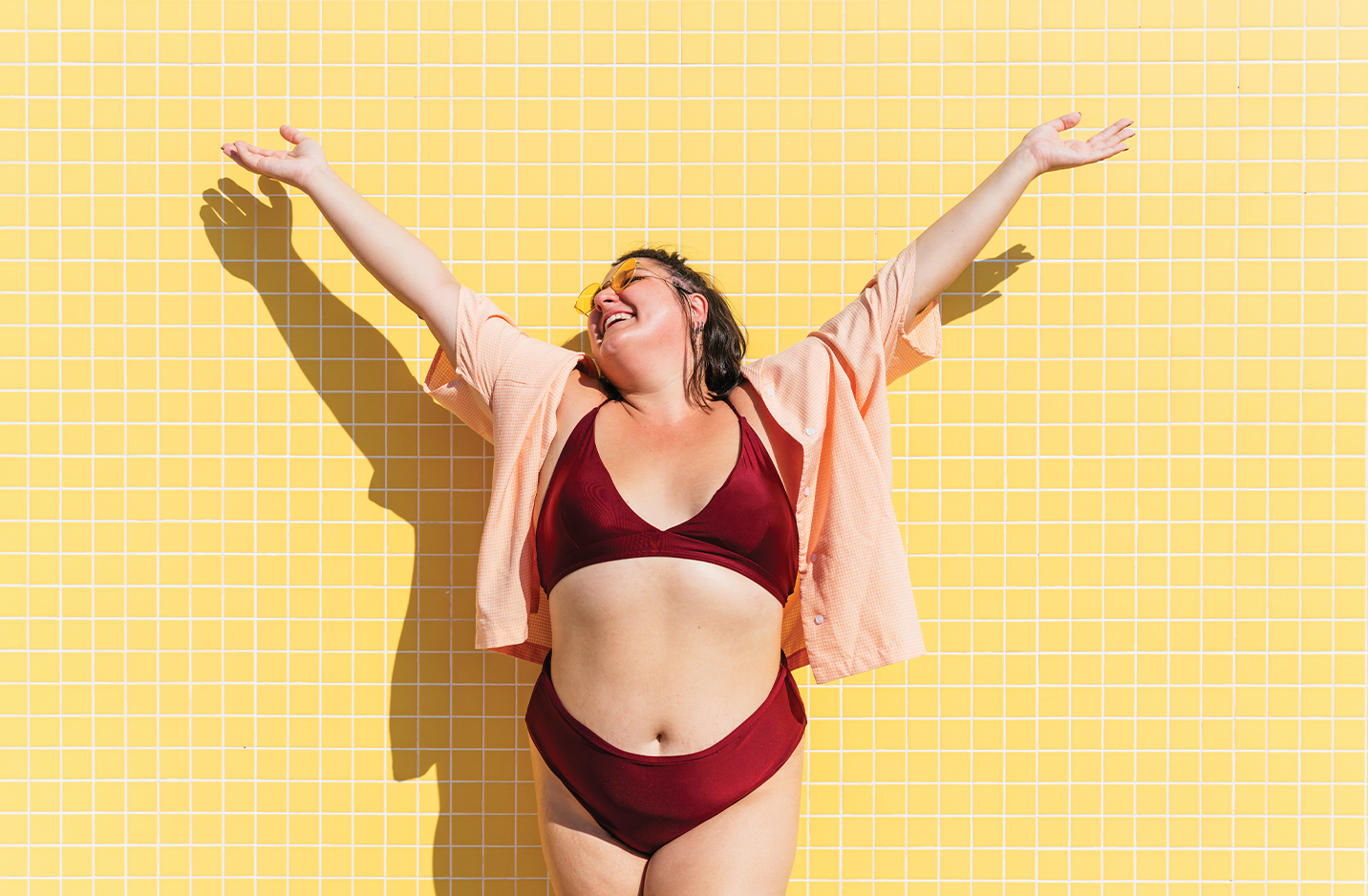 Female in bikini standing against a yellow brick wall