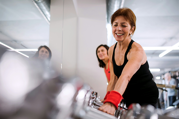 Middle aged female at the gym lifting a weight from rack