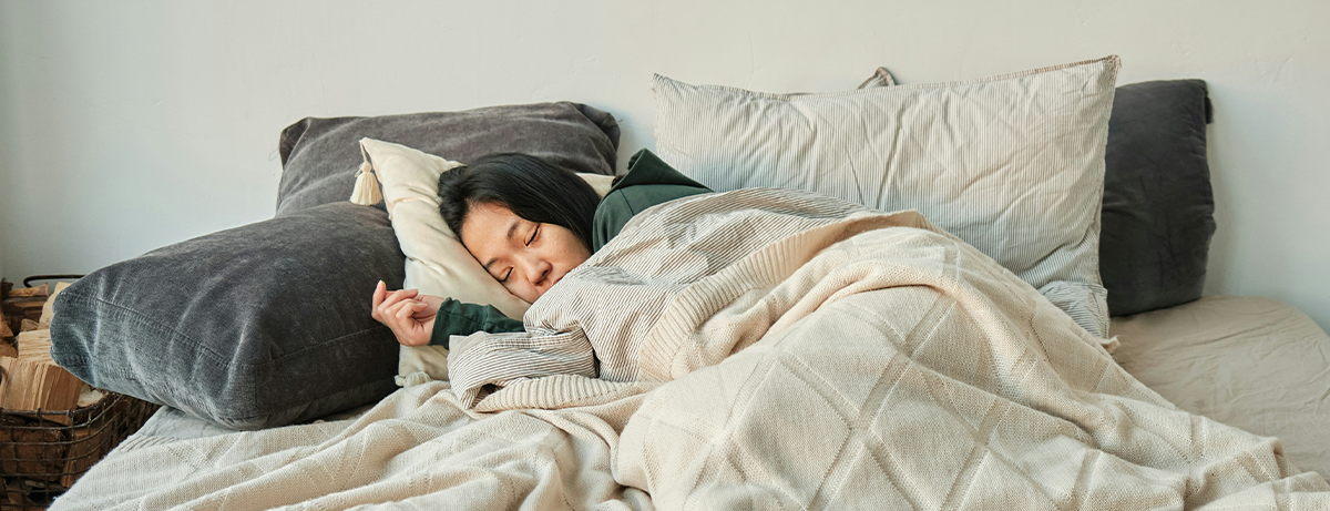 Female asleep in bed under blanket
