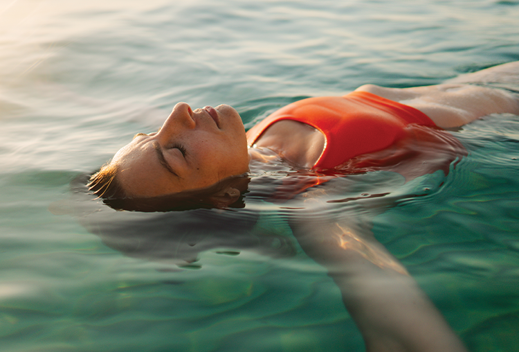 female laying on back in ocean, calm expression