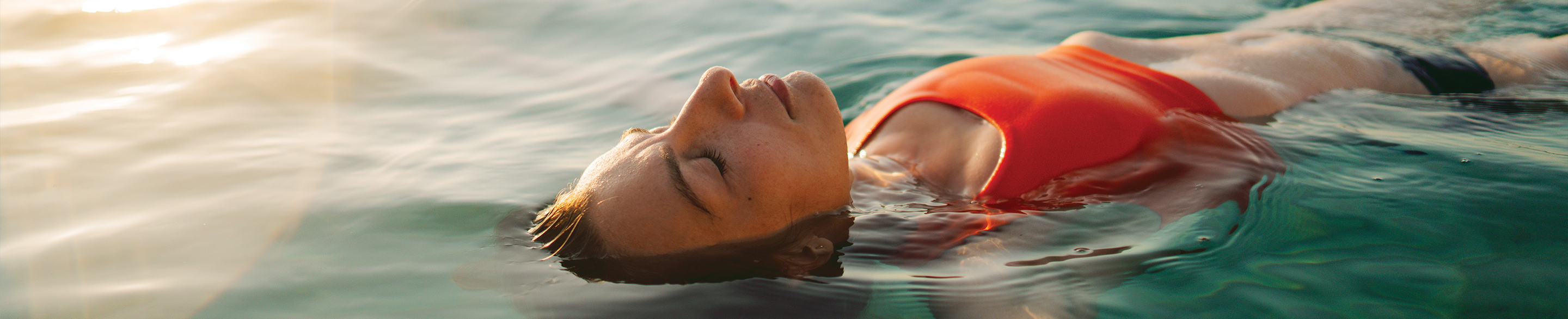 female laying on back in ocean, calm expression
