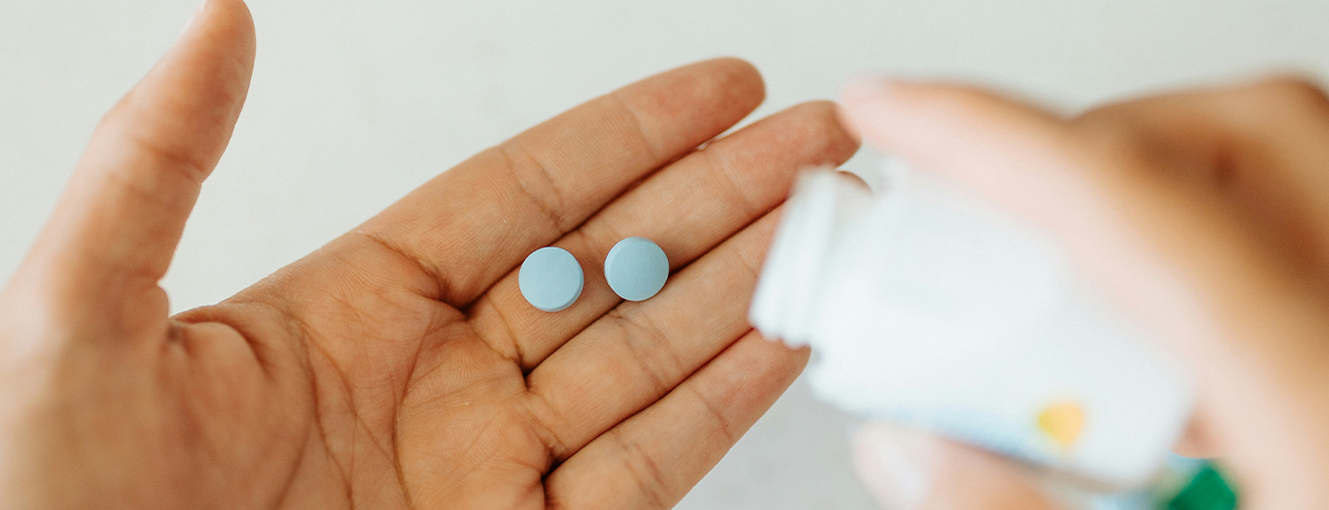Female holding 2 pills in hand out of bottle