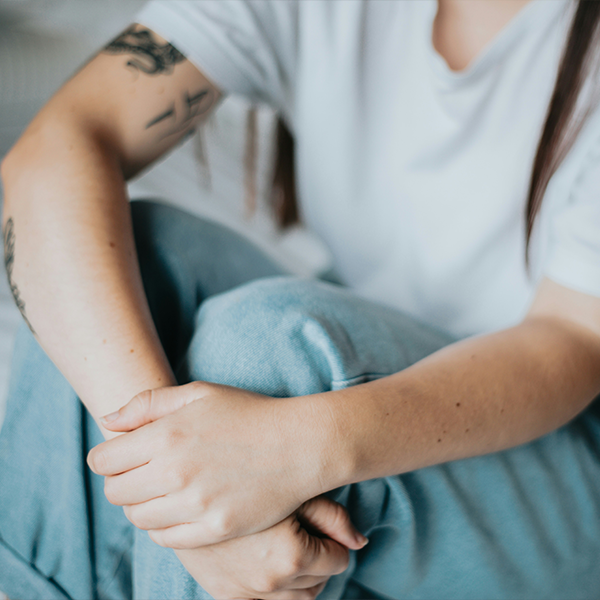 Female sitting on the bed with arms on leg.