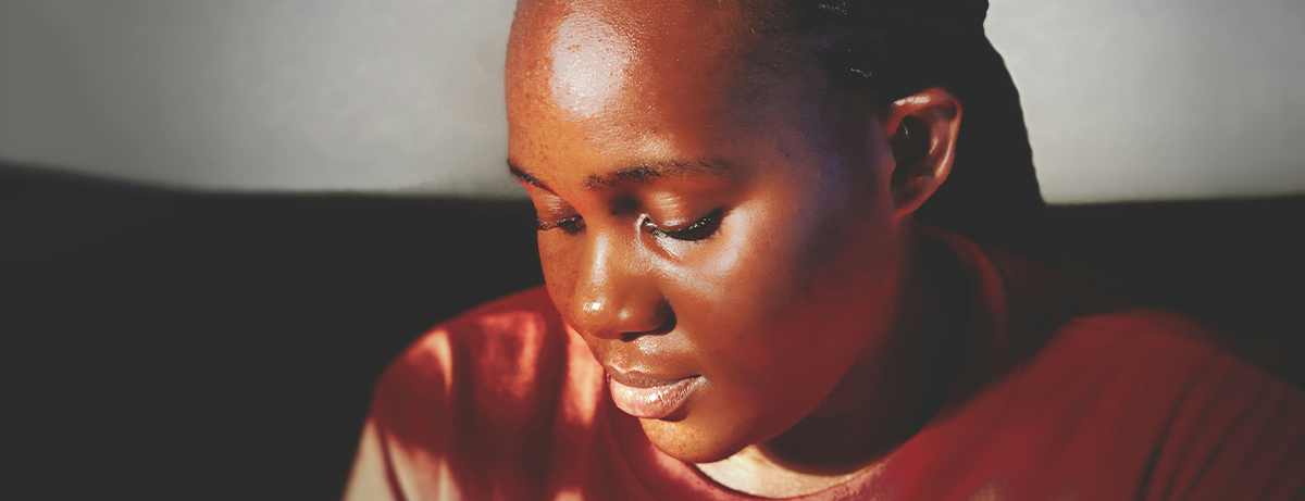 Female with calm expression looking down with sunlight on face