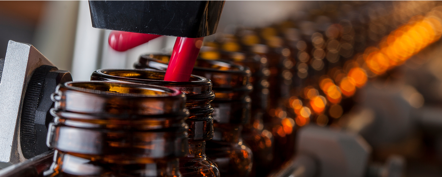 Red capsules being dispensed into brown glass bottles