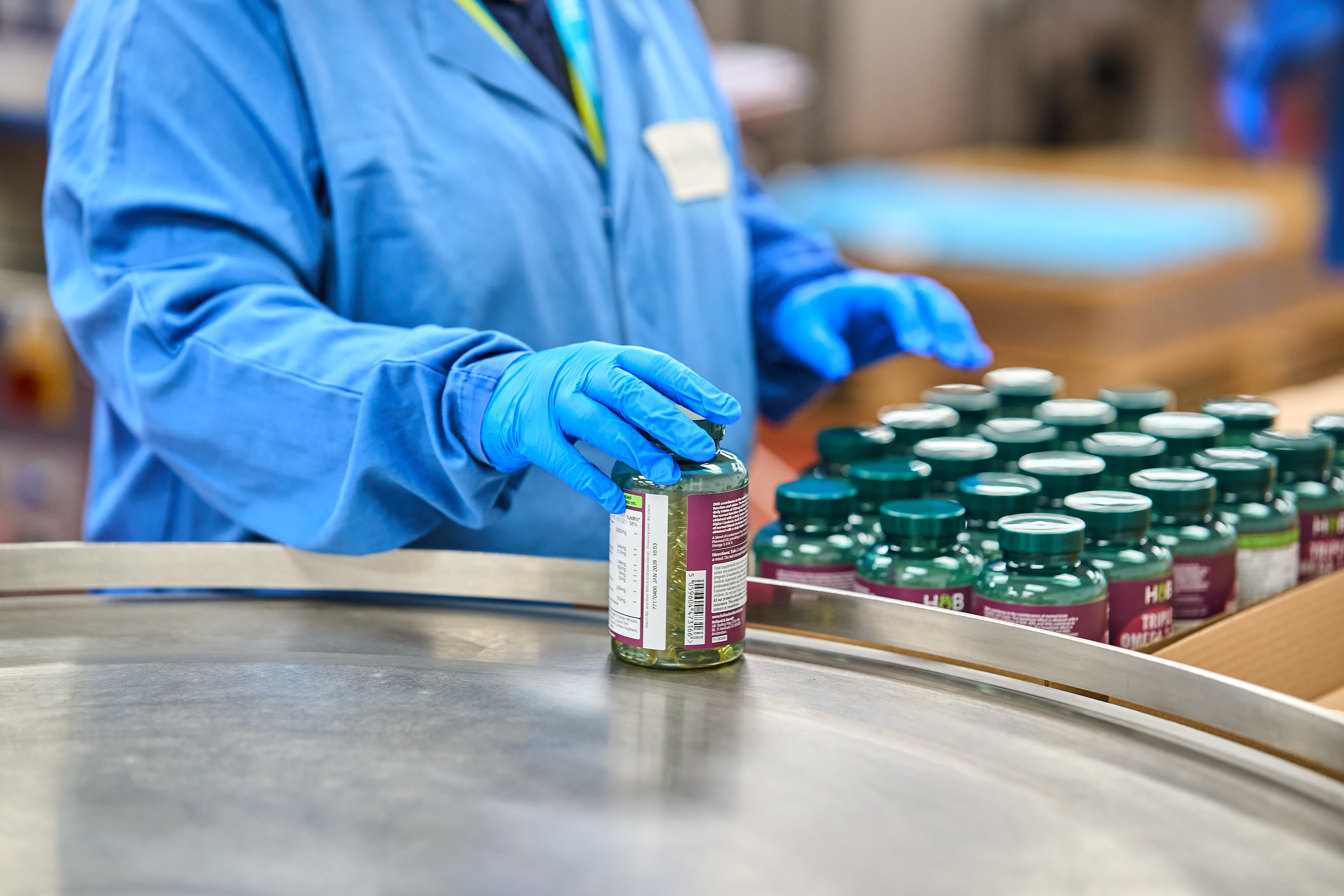 Production Operator in blue gown and gloves packing finished goods