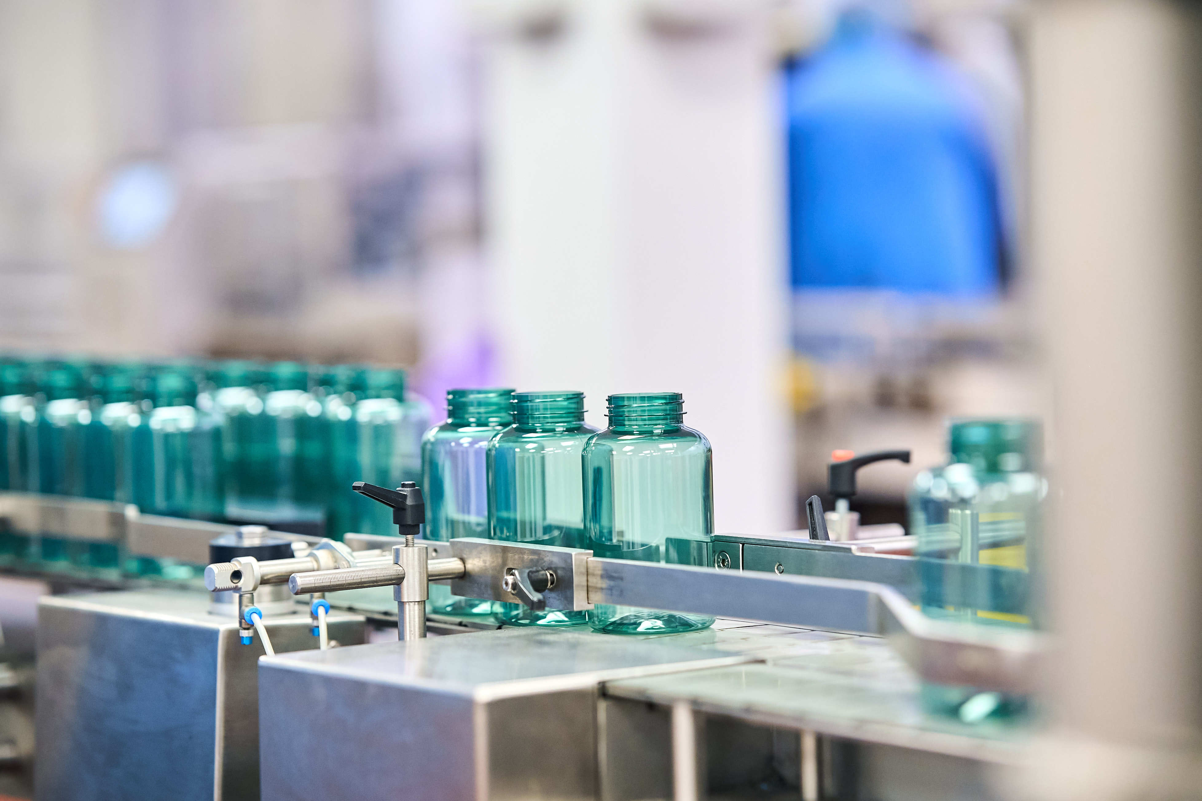 Empty translucent green bottles on the production line