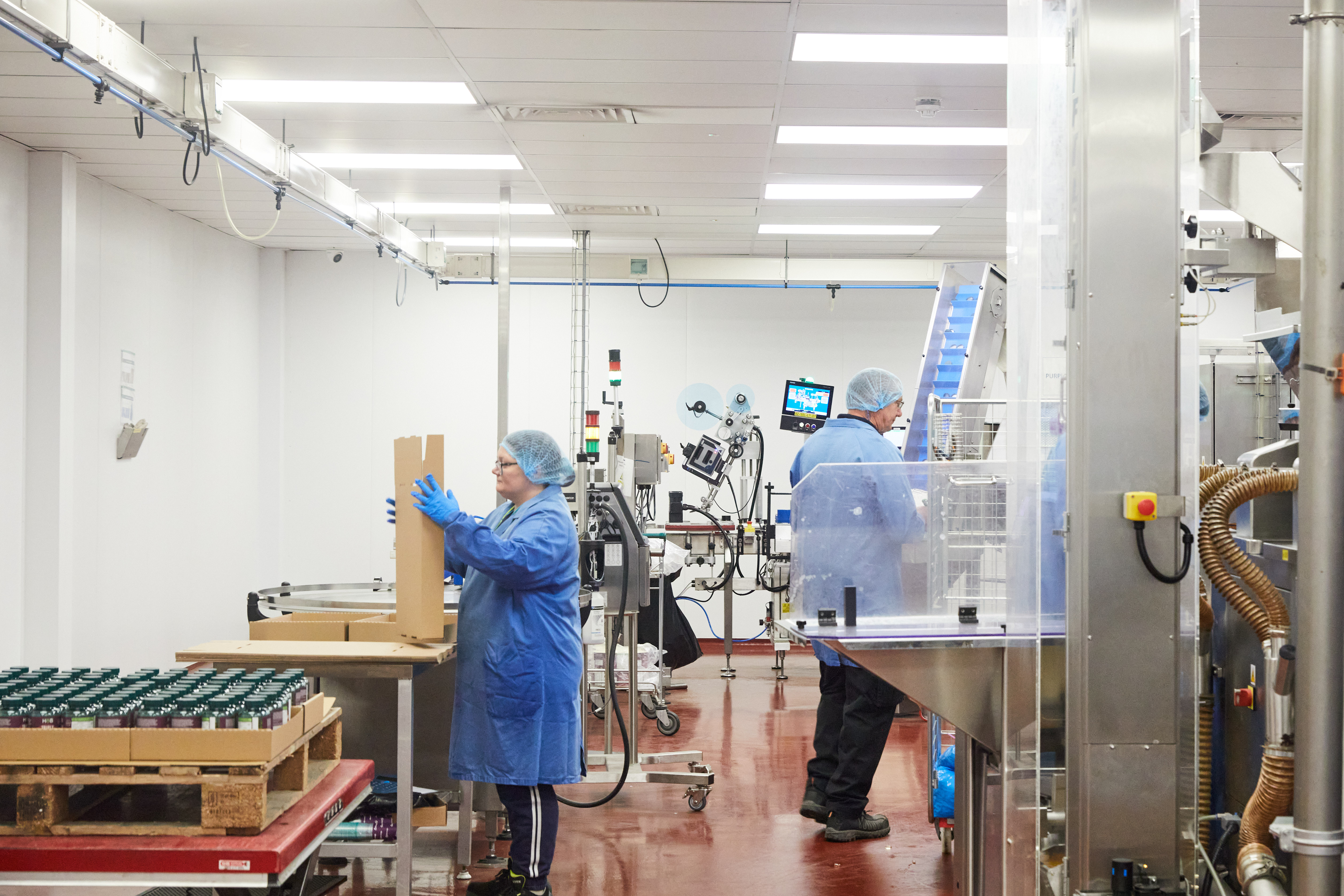 Production Operator in blue gown, hair net and gloves making packing trays