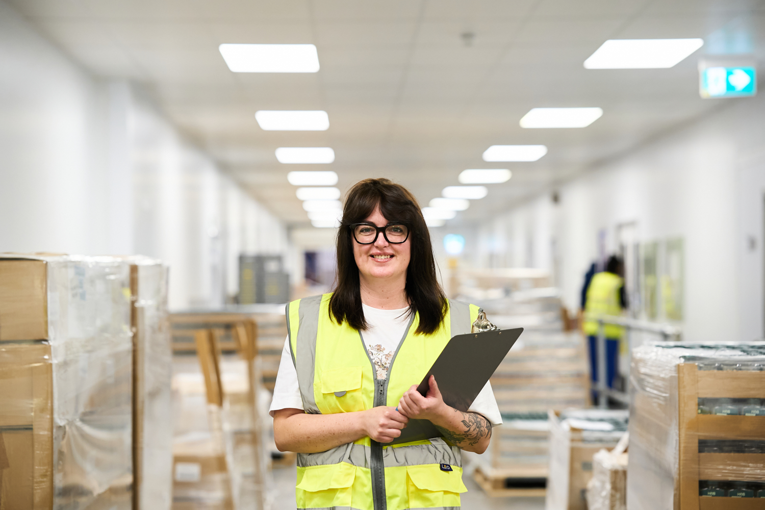 Smiling Compliance Officer in hi-vis vest with clipboard