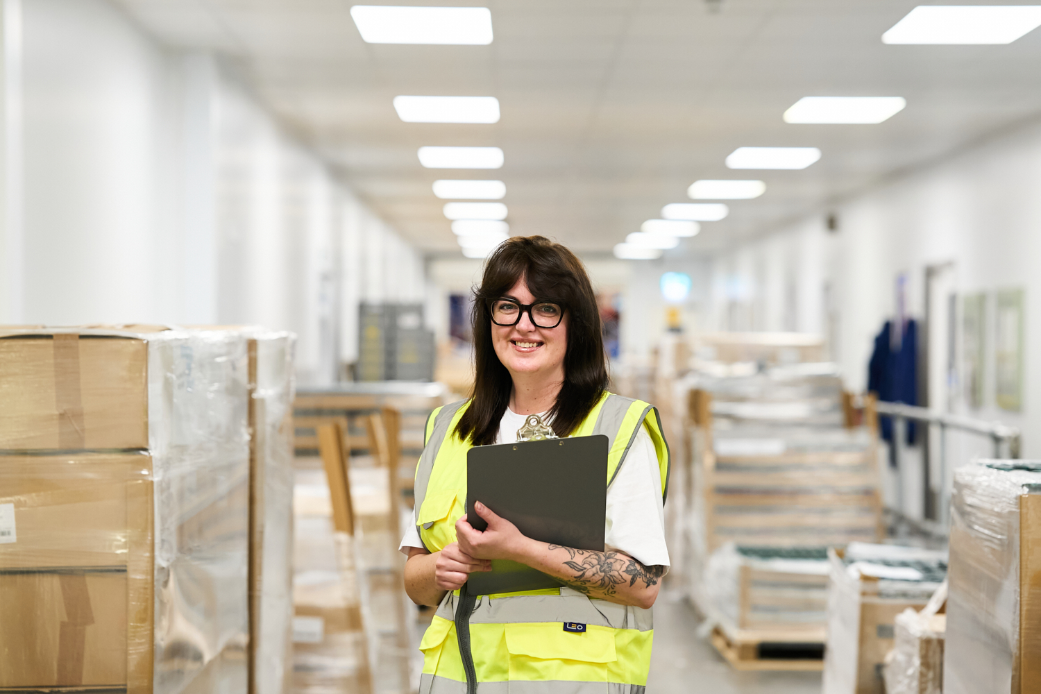 Smiling Compliance Officer in hi-vis vest with clipboard