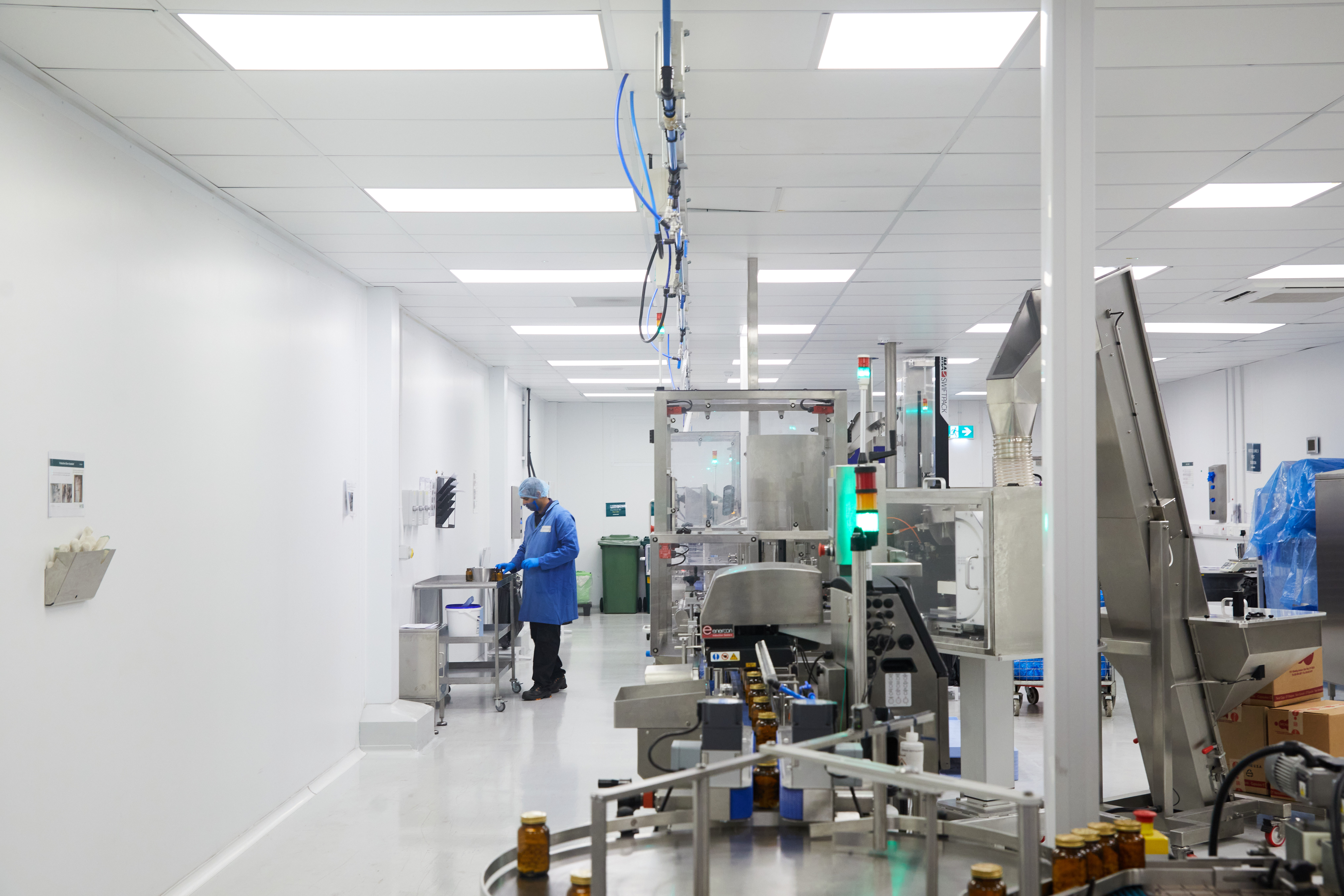 Production Operator in blue gown, hair net and gloves recording data during line run