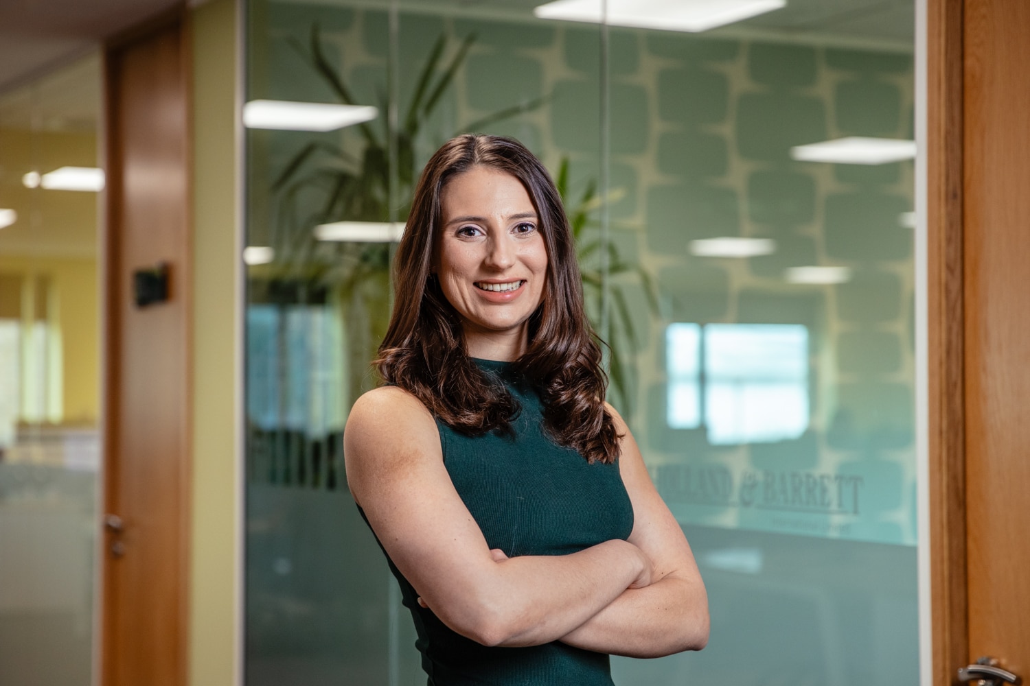 Colleague smiling and standing with crossed arms in the H&B office